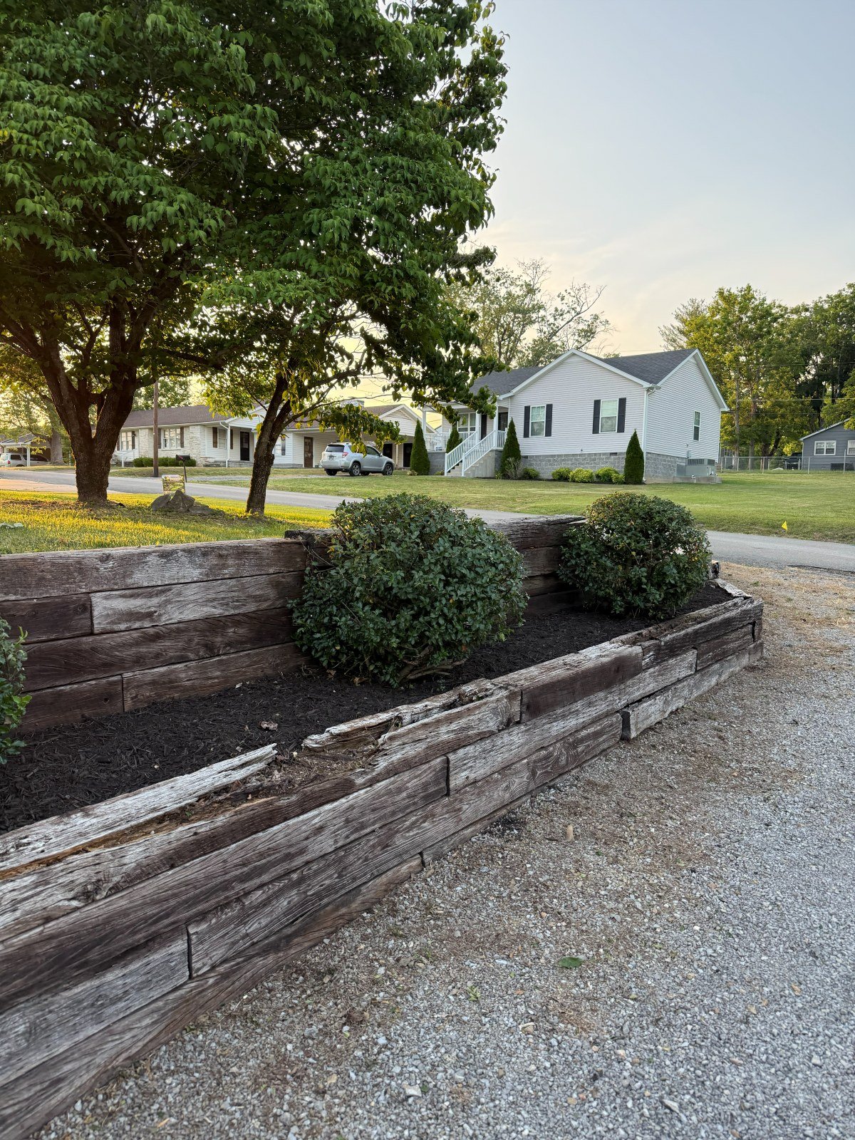 Timber retaining wall with fresh mulch and shrubs