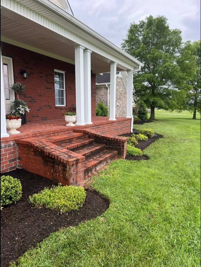 Mulched foundation bed along a brick front porch